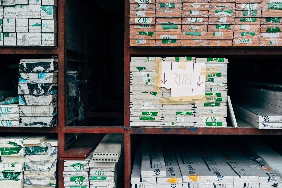 Organized stacks of building materials in a warehouse, highlighting the resources needed for roof replacement.