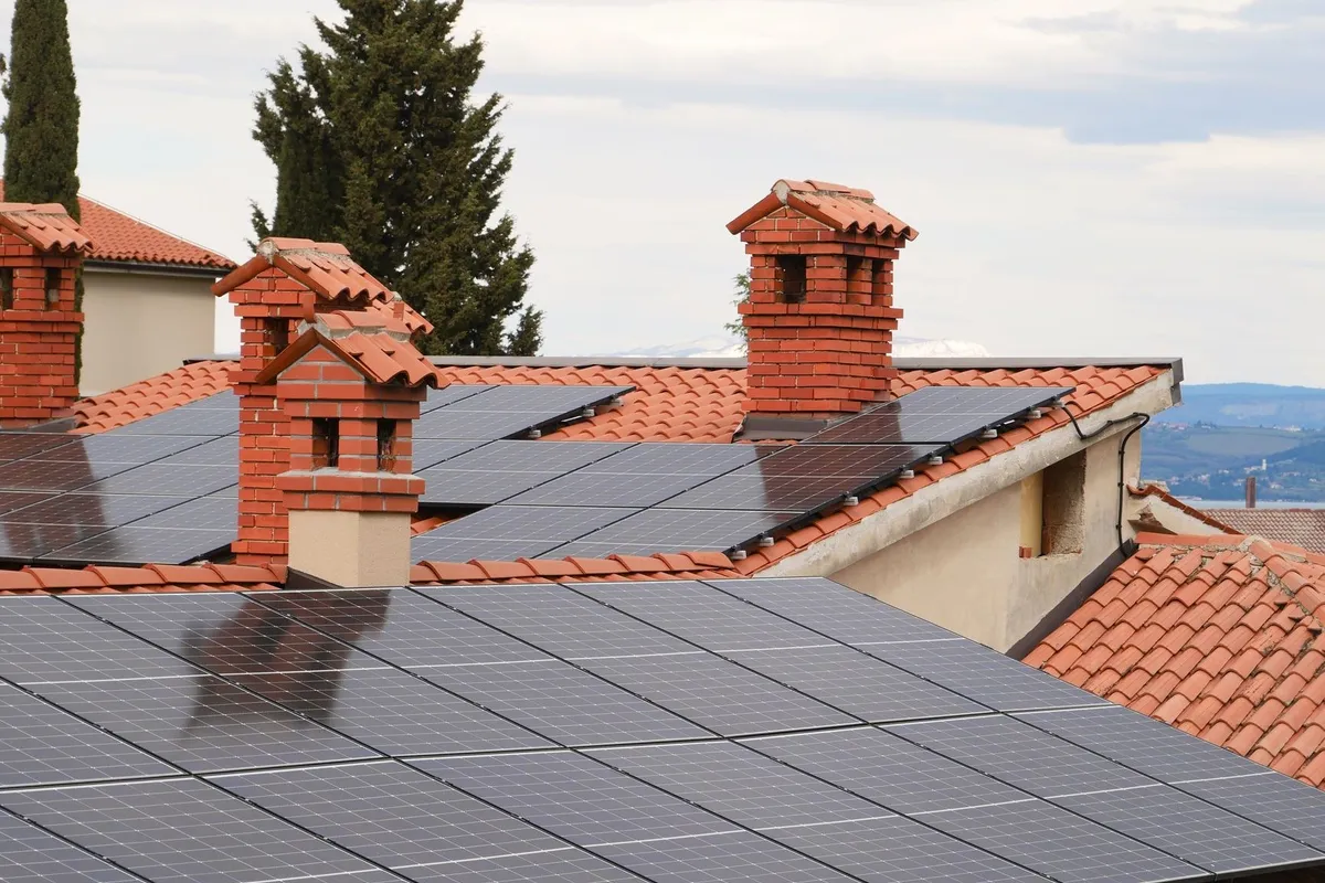 Solar panels on tiled roofs with chimneys, highlighting energy efficiency in roofing projects.